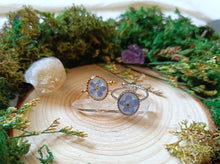 Load image into Gallery viewer, Two rings with forget-me-not cabochons on a wooden surface with greenery